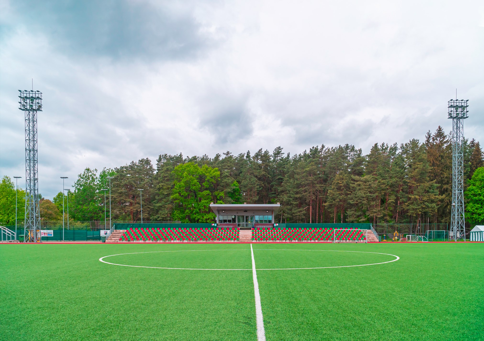 Olaines stadions, tribīnēm abās pusēs ir stabi ar  apgaismojumu